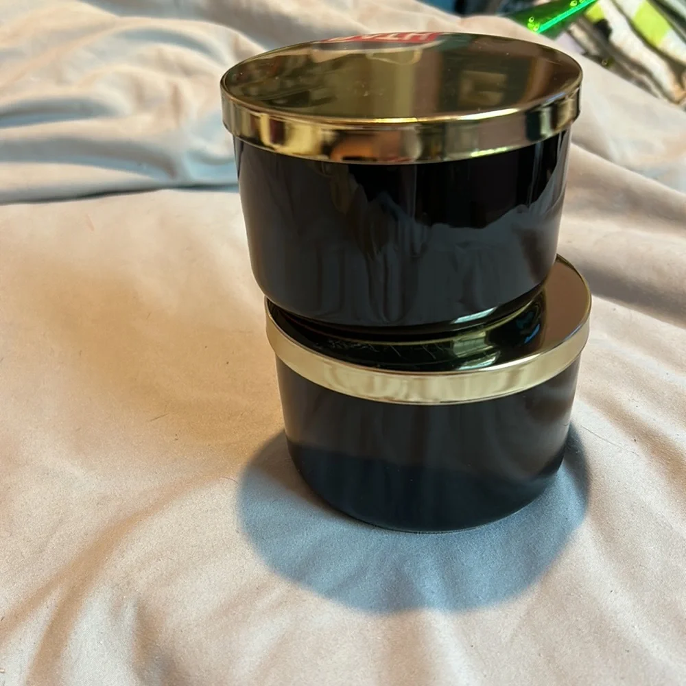 Two black jars with gold lids